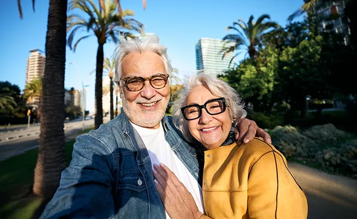 Older couple taking a selfie on a city walk, active again after knee treatment